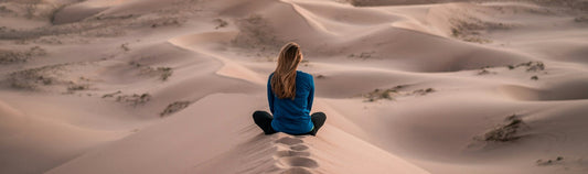 Mujer sentada en el desierto meditando | PorteinasMedellin.com