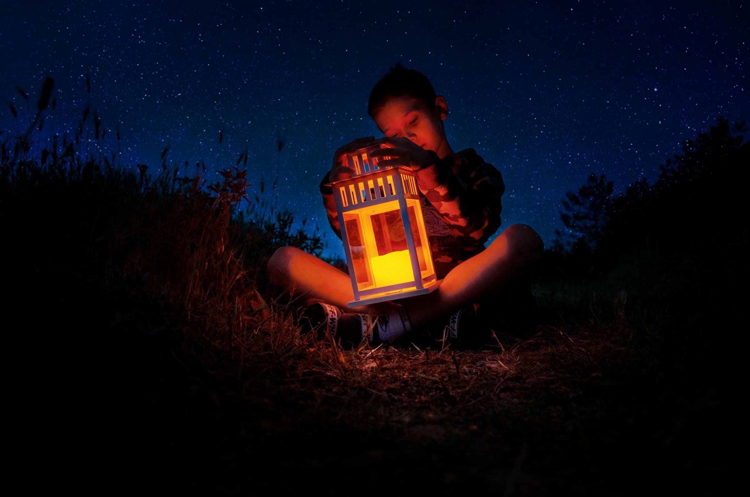Niño soñador mirando una lámpara bajo las estrellas | ProteinasMedellin.com